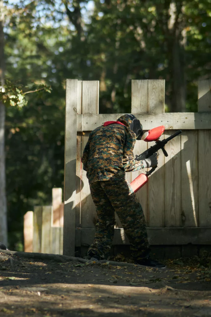 paintball player protective mask hides wooden barricade shoots paintballs paintball